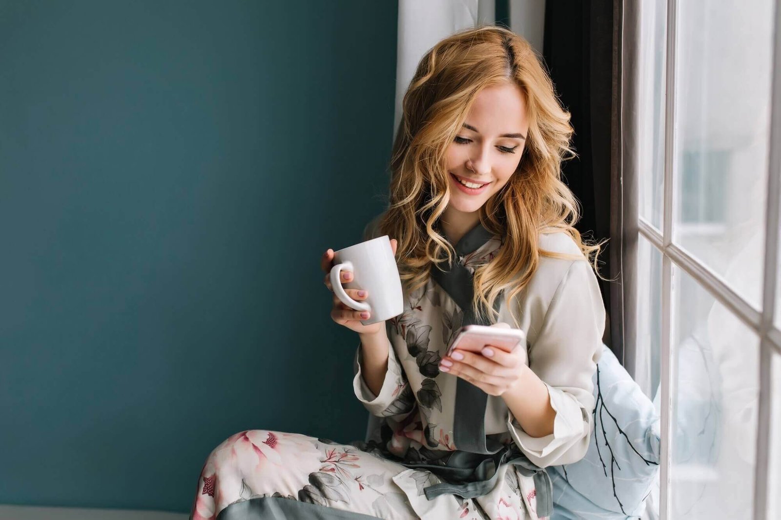 pretty blonde girl sitting window sill with cup